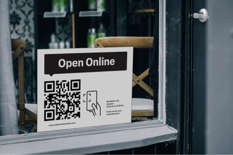 Window with a poster that says ’Buy online. Pick up curbside.’ with a QR code below the title.