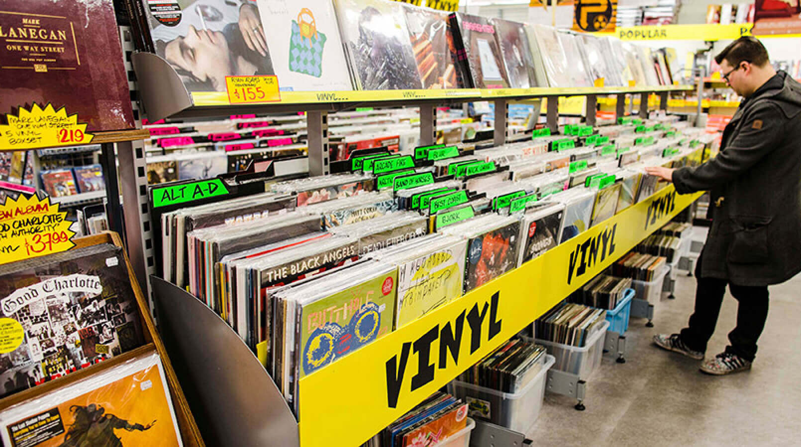 Man searching through racks of records inside JB Hi-Fi store.