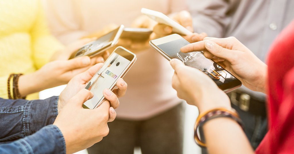 Various people hold up their phones with different Instagram Stories on their screens. 