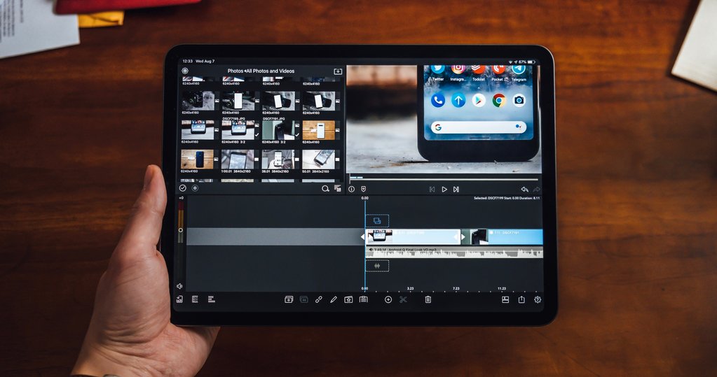 Overhead photo of person holding a tablet with video editing software in the screen.