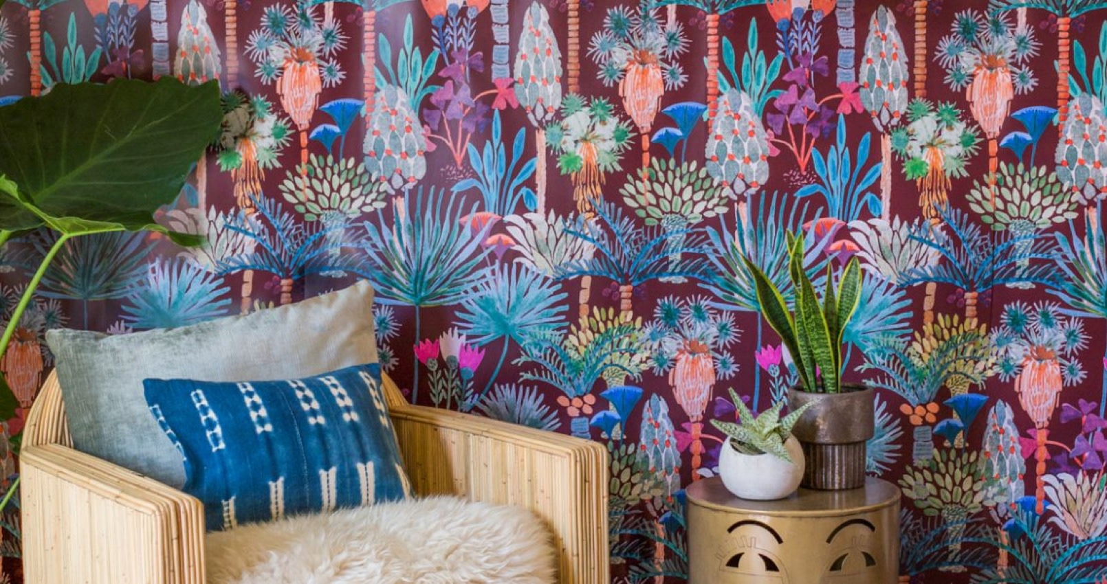 Wild, bright wallpaper is set as the backdrop for this reading nook, with wooded chair fitted with white plush cushions.