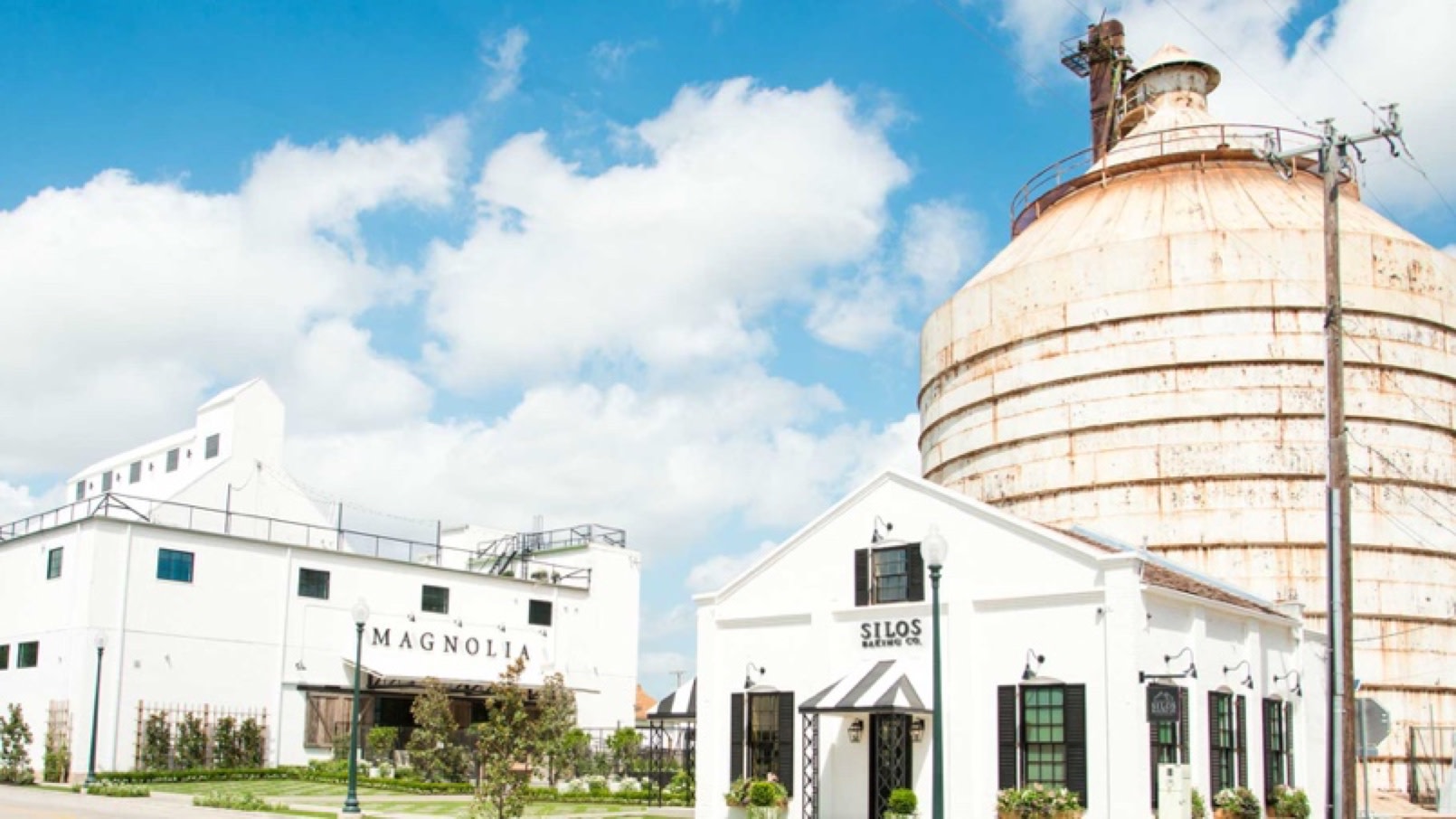 A landscape view of the Magnolia Silos, a sprawling retail complex in Texas with white buildings and a green, manicured lawn.