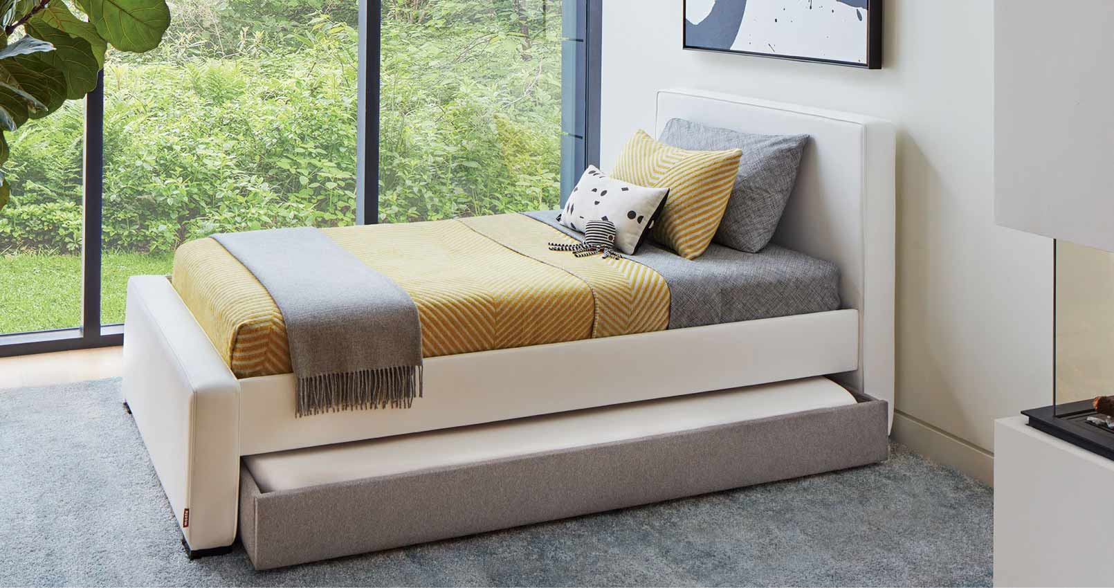 A comfortable looking captain style bed with orange, grey, and white pillows and blankets.