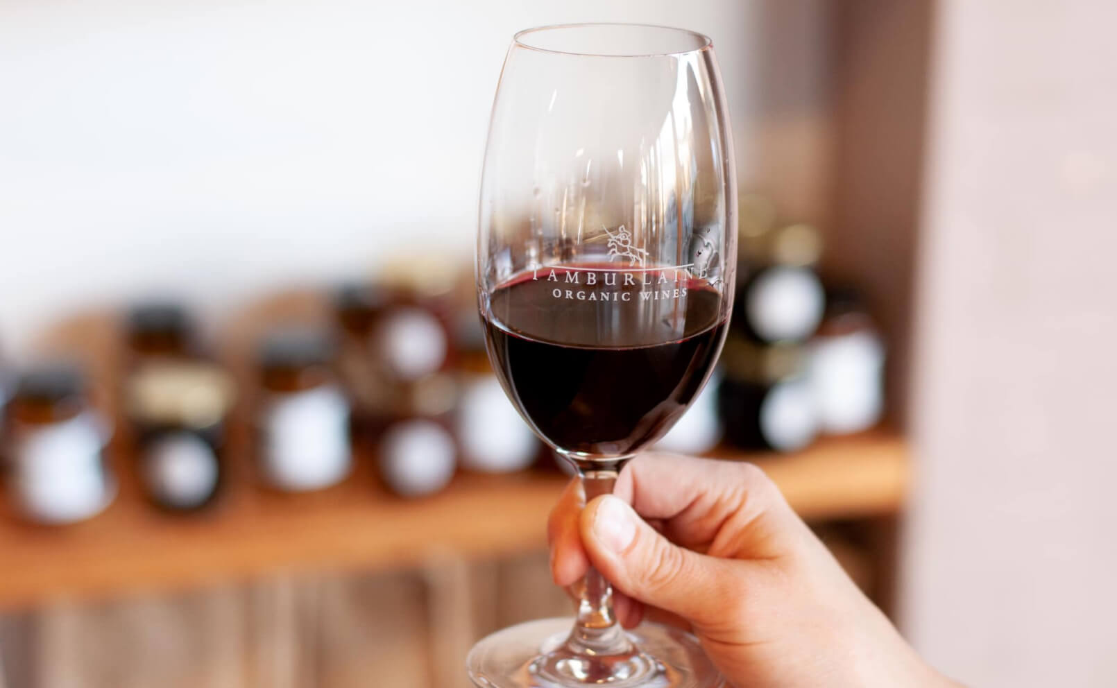 Person holding a glass of red Tamburlaine Organic Wine